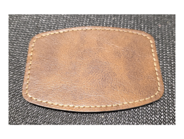 Brown leather patch with stitching on a textured black surface.