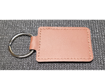 Pink leather keychain with metal ring on textured surface.